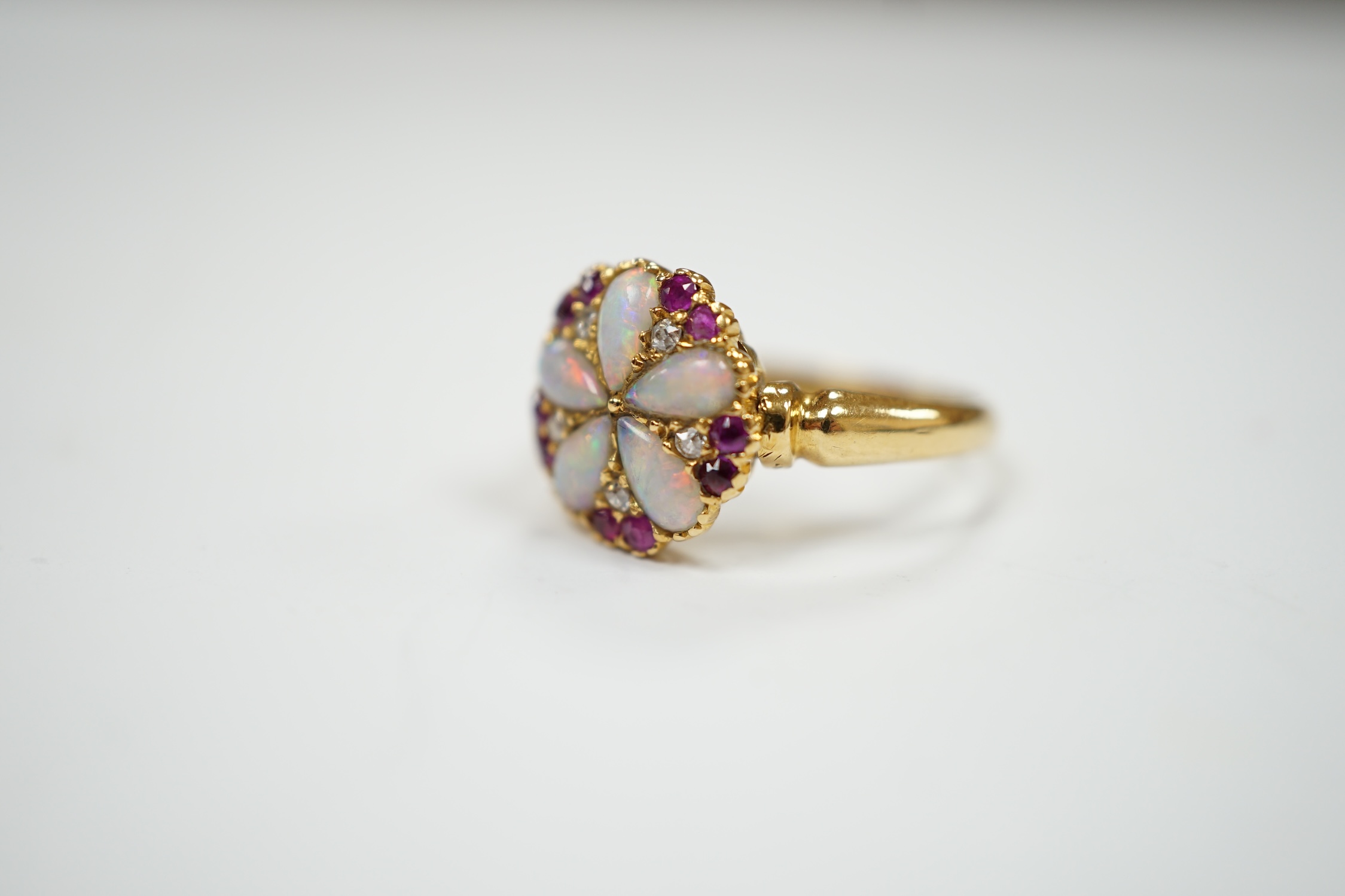 An Edwardian 18ct gold, white opal, ruby and diamond cluster set ring, size K, gross weight 3.1 grams.